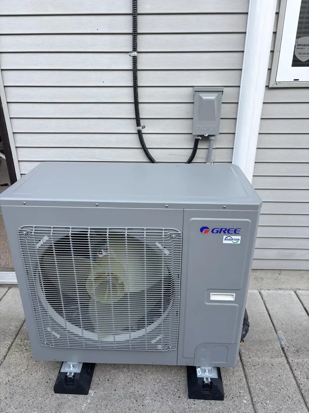 Outdoor heat pump unit installed on pads beside a house