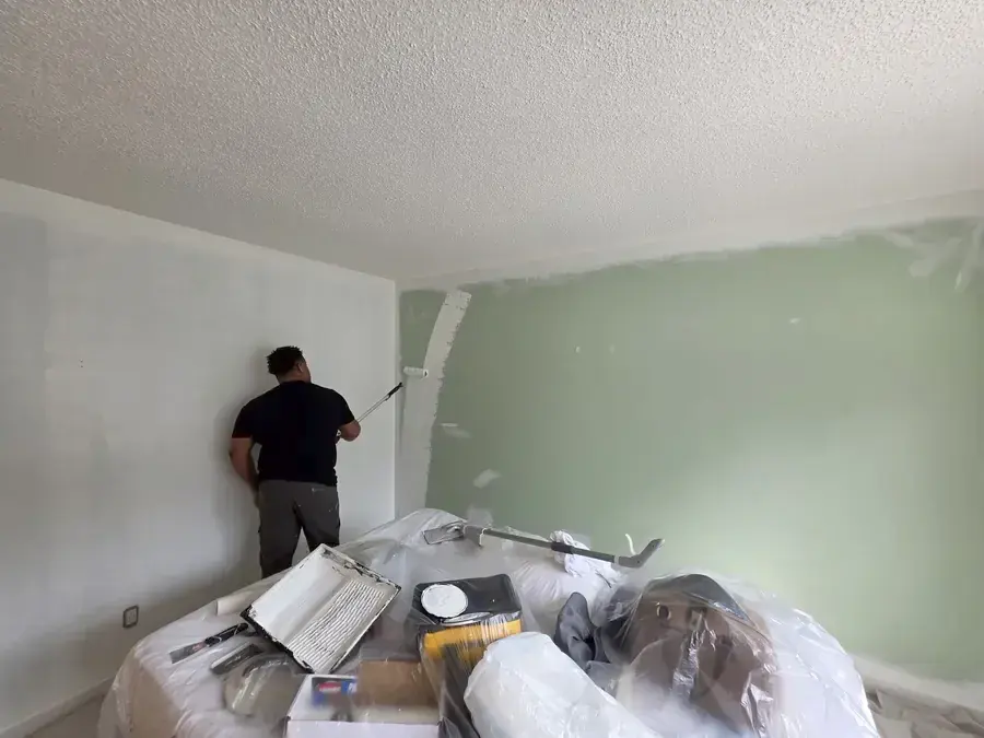Fresh sage-green accent wall being painted by an Imagination Renovations crew member