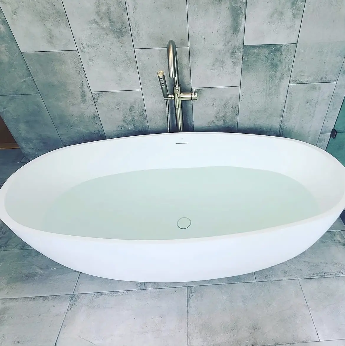 Oval freestanding tub with brushed nickel floor-mounted filler
